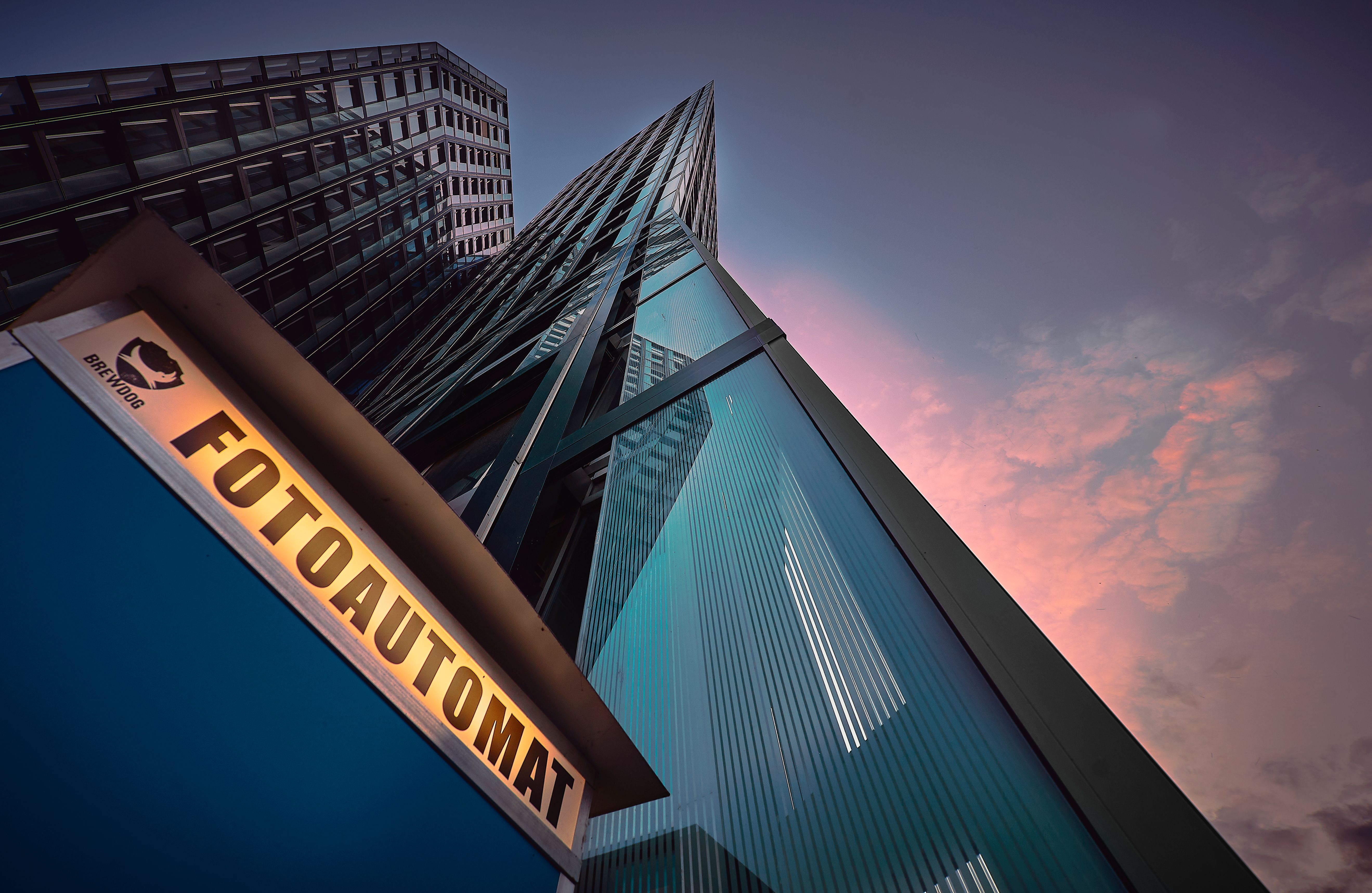 Low-angle view of a modern skyscraper with a glass facade against a twilight sky.