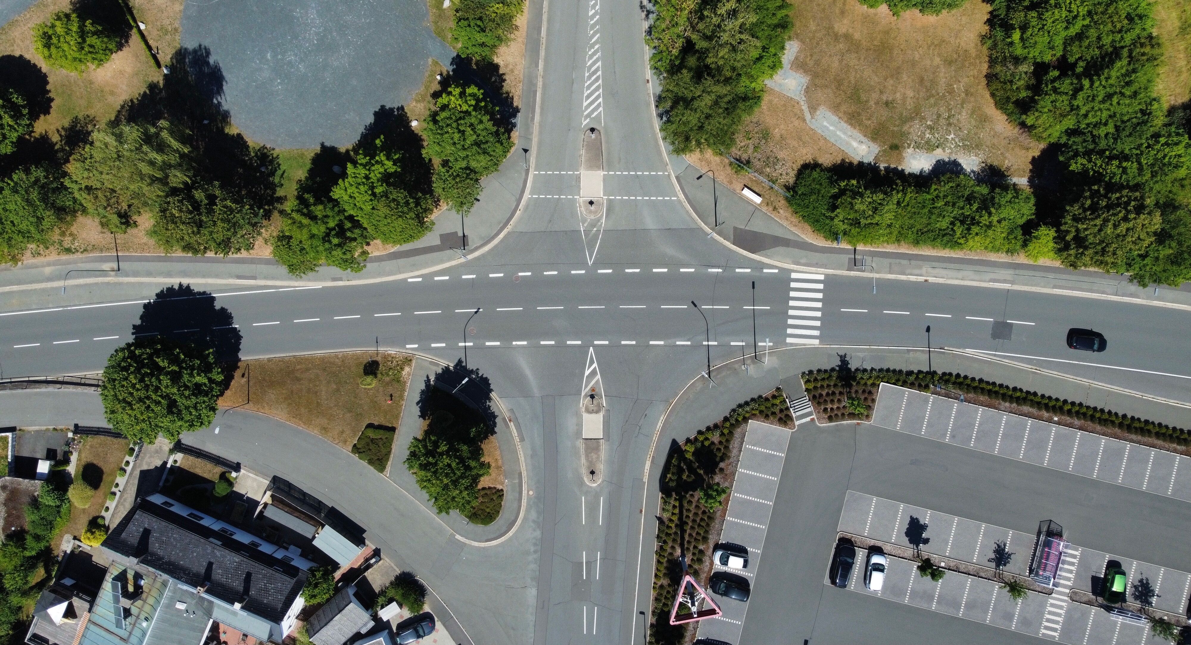 Aerial shot of a sunlit intersection surrounded by greenery in Rehau, Germany.