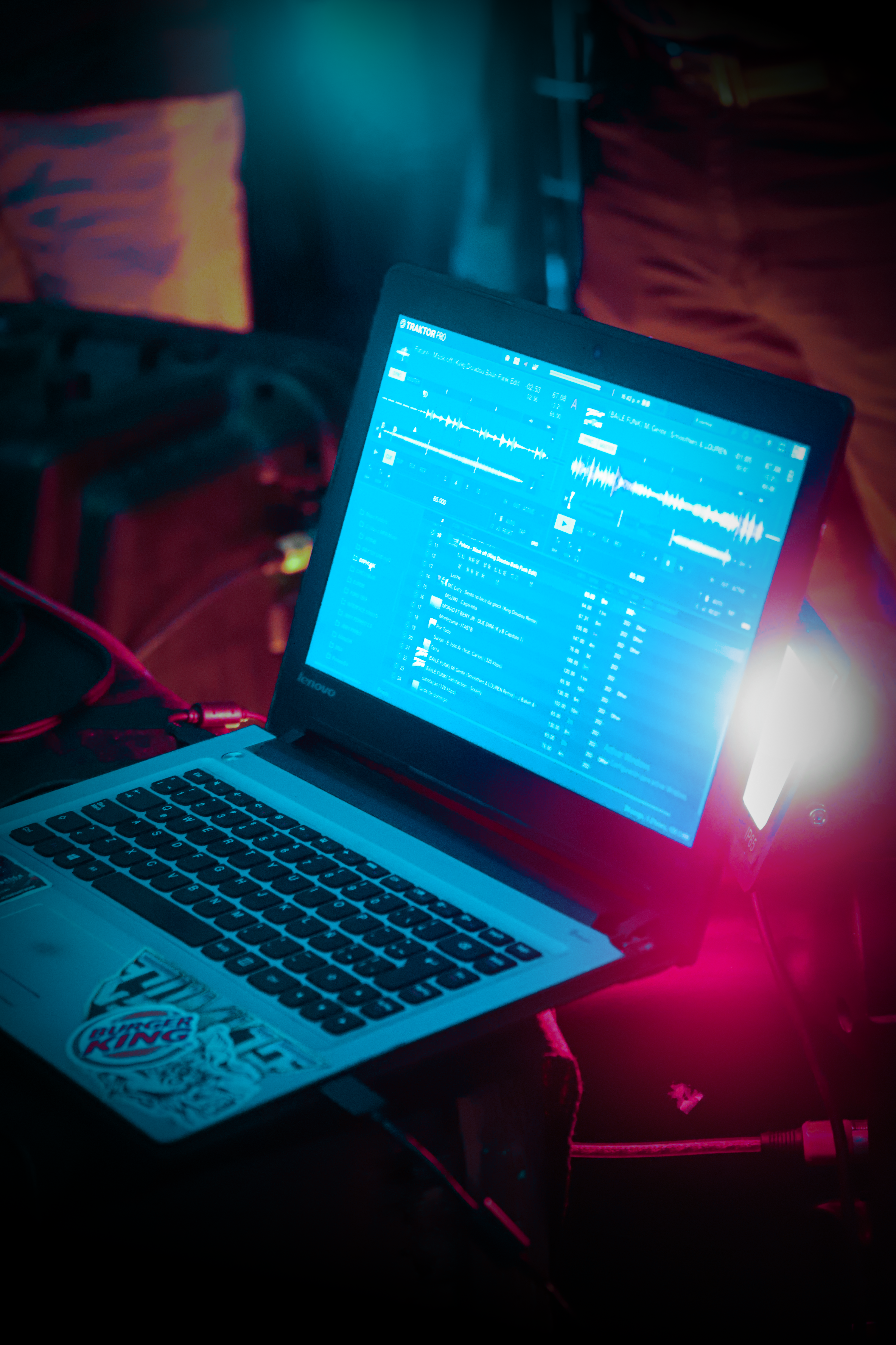 Nightclub DJ laptop displaying music mixing software with waveforms, creating a vibrant nightlife ambiance.