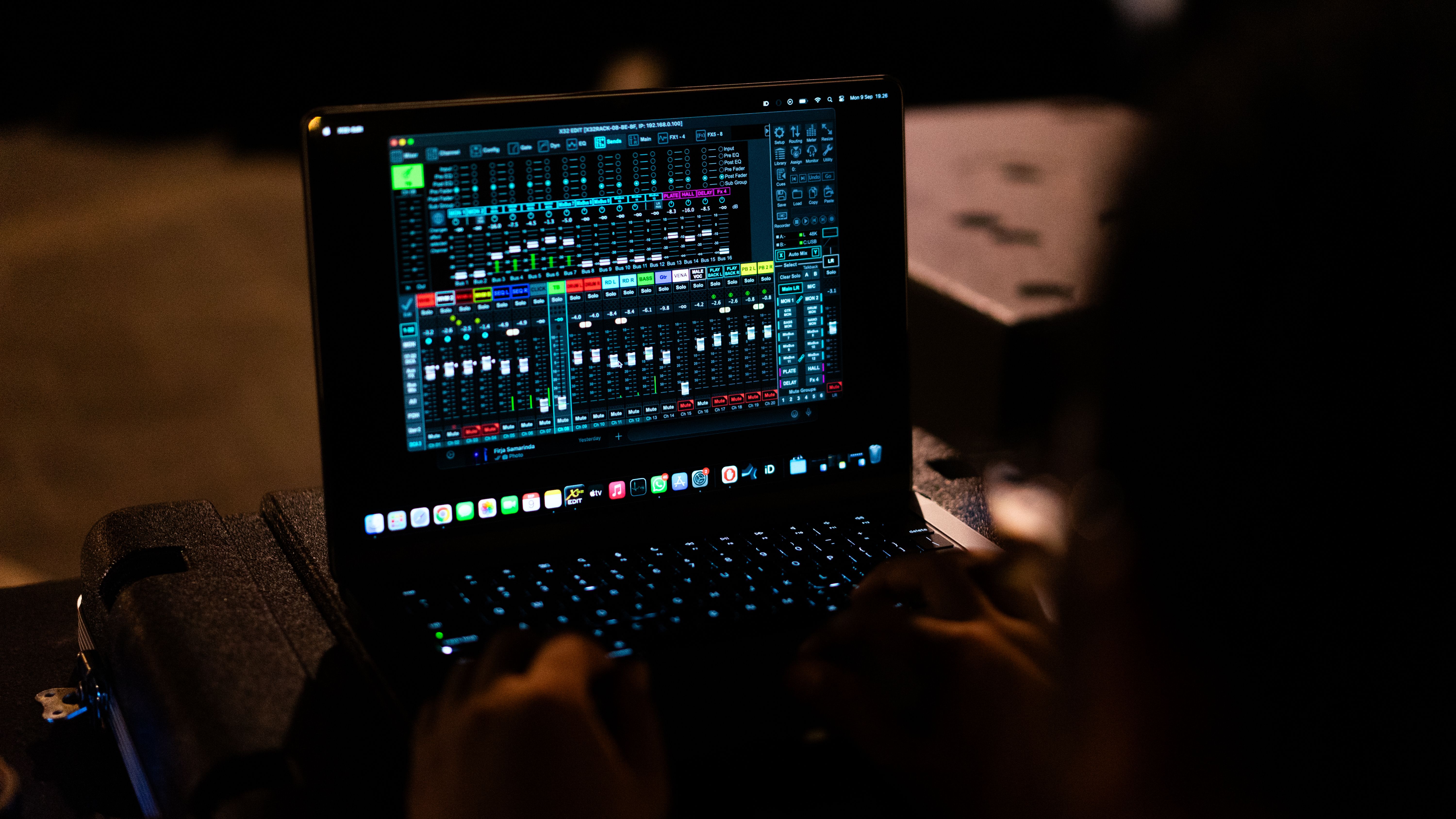 A sound engineer adjusting audio settings on a digital mixer via a laptop.