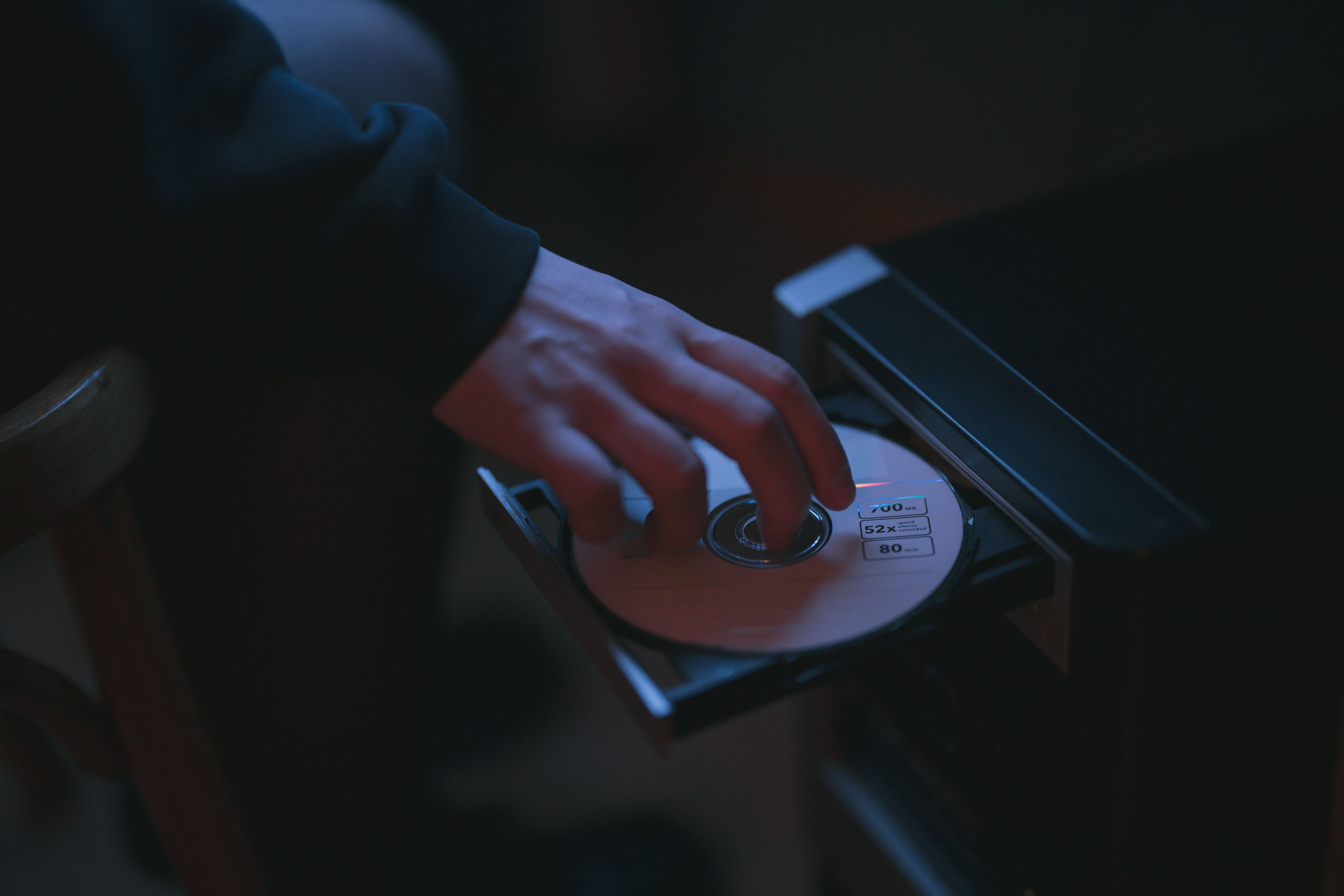 A hand inserting a CD into a computer drive, highlighting cyber security themes.