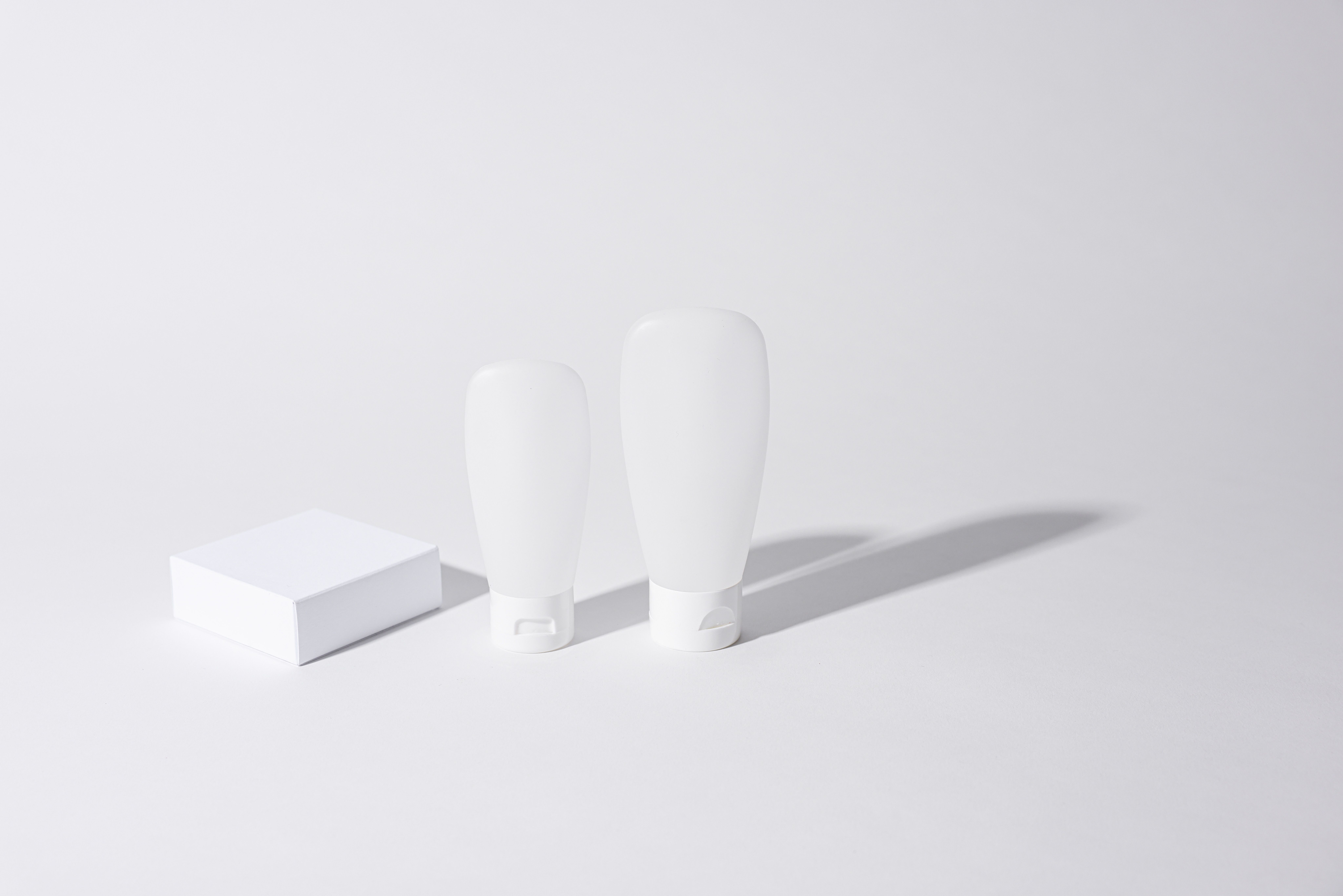 Minimalist mockup of cosmetic containers with empty white packaging, ideal for branding.