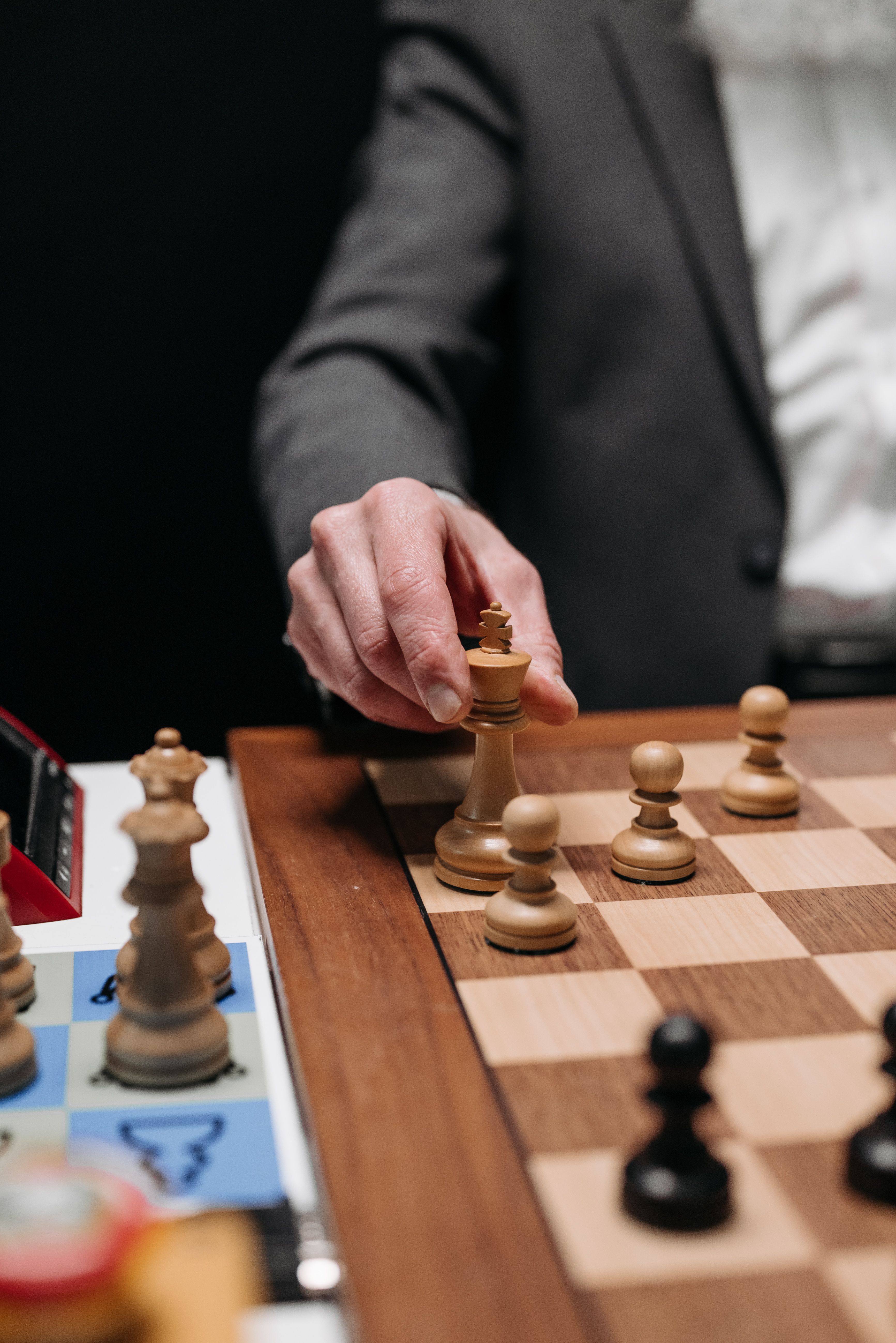 Close-up of a person making a strategic move on a chessboard during an intense game.